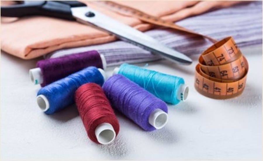 Sewing threads, scissors and a tape measure on a work table