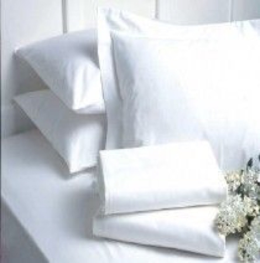 Clean folded white bed linen and pillows